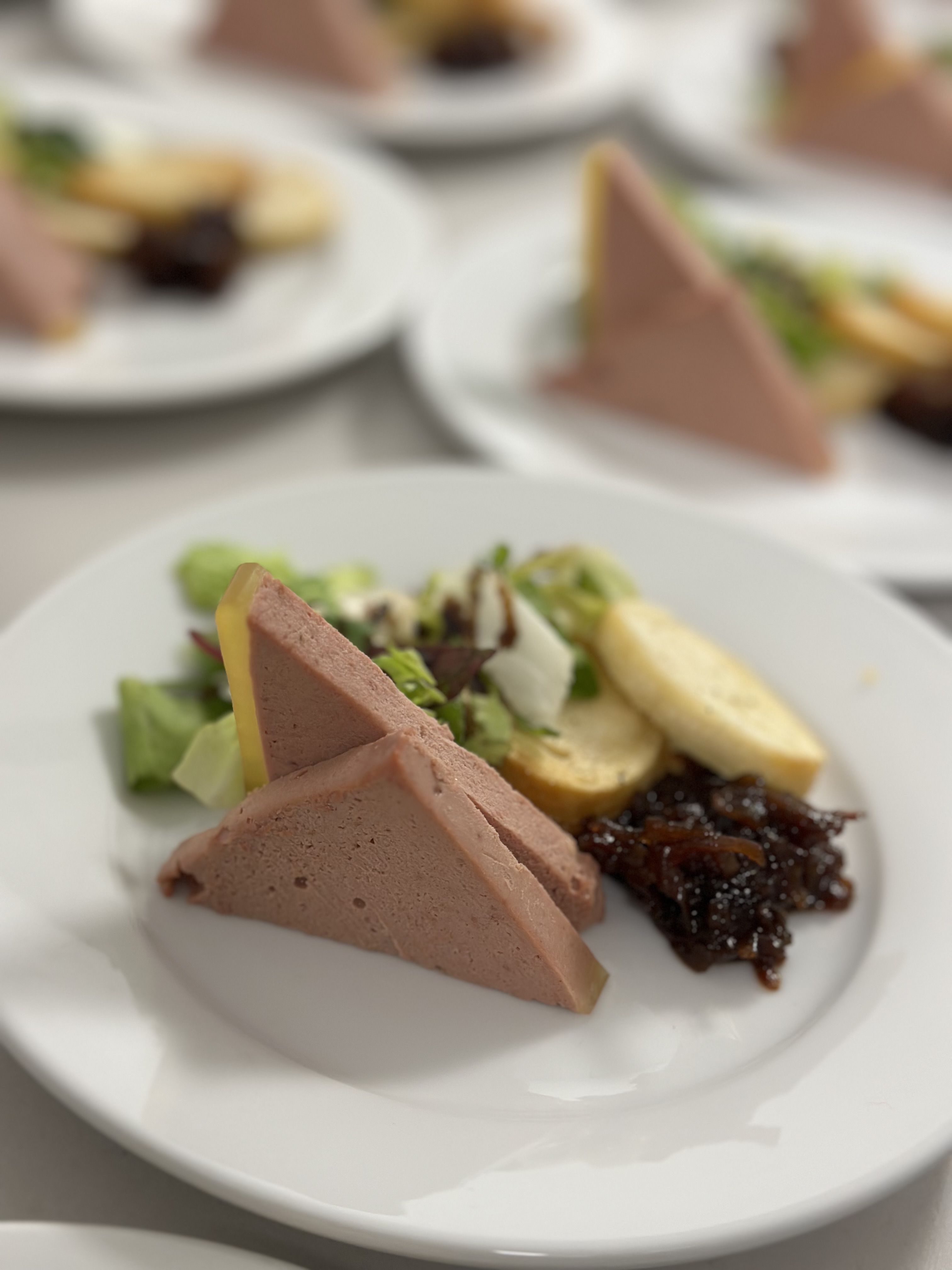 The photo shows several plates with duck pate and a side salad on it ready to go and be served.