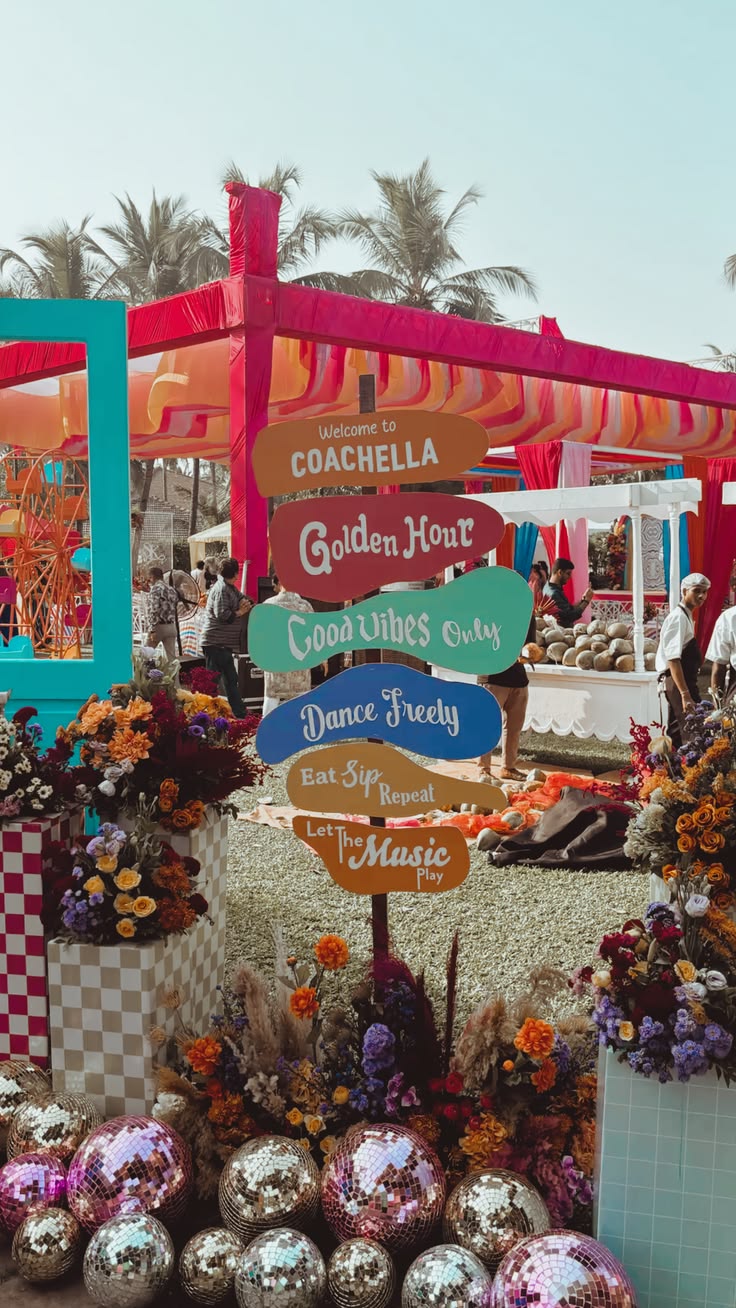 The image shows a Coachella-themed party with a colourful wooden sign, disco balls and flowers.